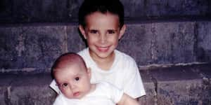 Jona sitting on some stairs holding his brother.