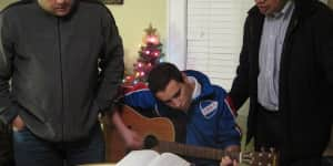 Jona playing the guitar and singing with his dad and a friend.