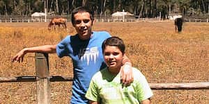 Jona leaning against a wooden fence with his brother, Marcos.