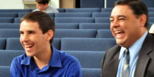 Jona and his dad sitting in their church auditorium, laughing.